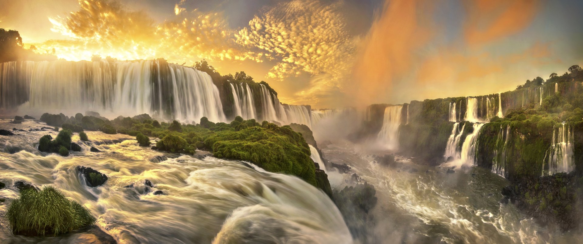 A stunning sunset illuminates Iguazu Falls in Brazil, showcasing vibrant hues and cascading water against a backdrop of lush greenery, creating a breathtaking natural scene.