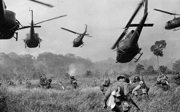 Black and white Vietnam War scene with military helicopters hovering over soldiers advancing through tall grass, captured as an HD PC desktop wallpaper and background.