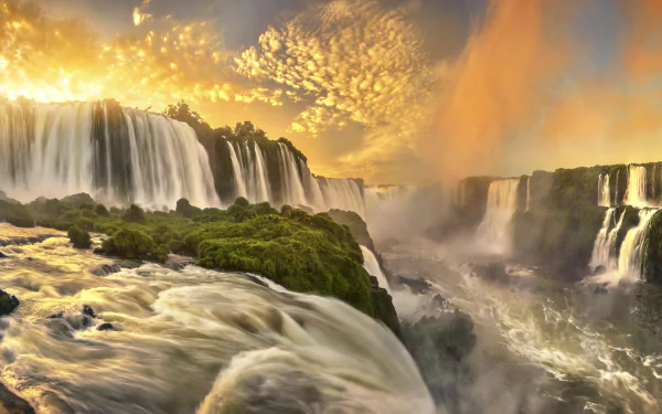A stunning sunset illuminates Iguazu Falls in Brazil, showcasing vibrant hues and cascading water against a backdrop of lush greenery, creating a breathtaking natural scene.