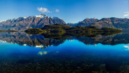 A stunning HD wallpaper of a New Zealand lake with crystal-clear reflections of majestic mountains under a bright blue sky, creating a serene panorama of nature's beauty.