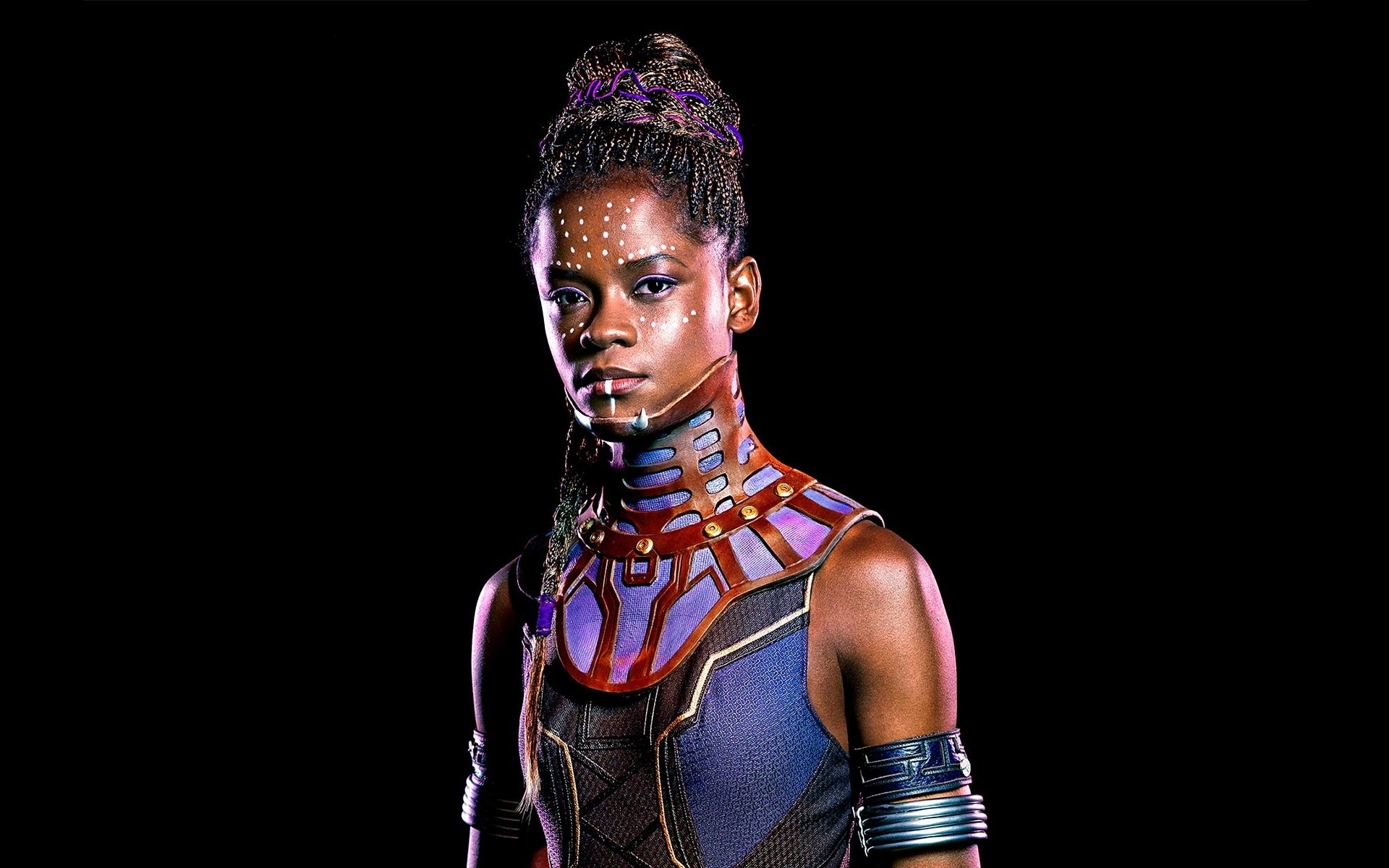 HD desktop wallpaper and background image of a character from the movie Black Panther, featuring a young woman adorned with detailed tribal makeup and attire, standing against a dark background.