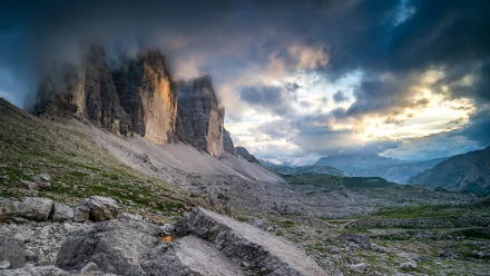 Dramatic landscape of Tre Cime di Lavaredo cliffs under moody clouds, showcasing rugged nature in an HD desktop wallpaper background.