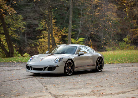 Silver Porsche 911 Carrera parked on a paved road surrounded by autumn trees, captured in HD for a striking desktop wallpaper background.
