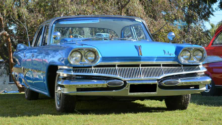 A blue Dodge Phoenix sedan showcased as an HD PC desktop wallpaper, highlighting the classic car's polished chrome grille and vintage design.
