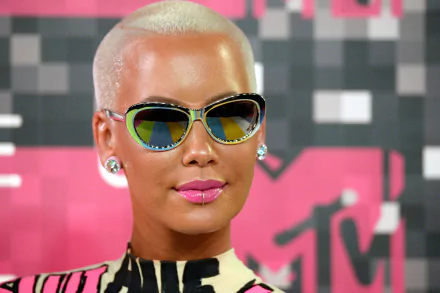 HD desktop wallpaper featuring a person with blonde buzz cut and reflective sunglasses against a pink graphic background.