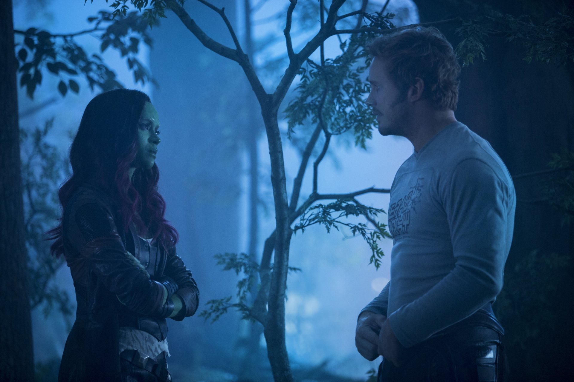 Star-Lord and Gamora stand facing each other in a blue-lit forest scene from Guardians of the Galaxy Vol. 2 — 5K Ultra HD PC desktop wallpaper.