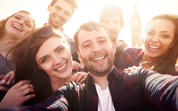HD wallpaper of a joyful group of friends taking a selfie in bright sunlight, embodying friendship and happiness.