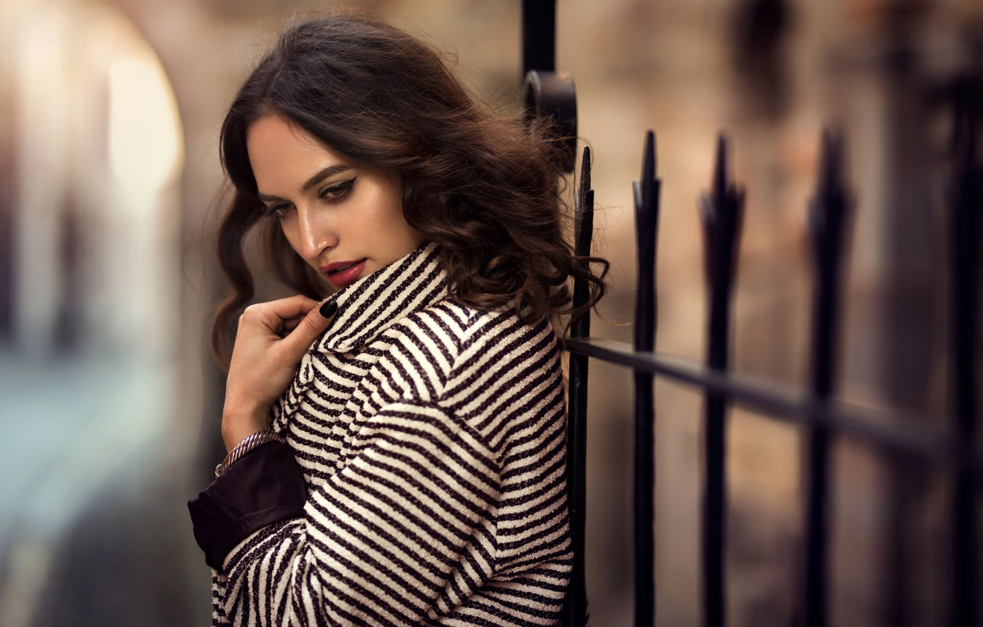 A brunette woman with brown eyes and bold lipstick poses thoughtfully against a blurred background, showcasing mood and depth of field in this HD desktop wallpaper.