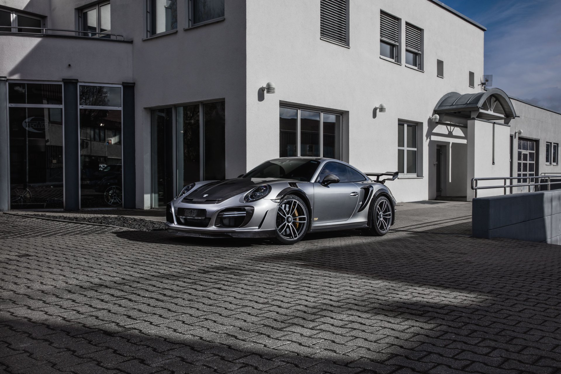 Silver Porsche 911 Turbo parked in front of a modern building, showcased as an HD PC desktop wallpaper and background.
