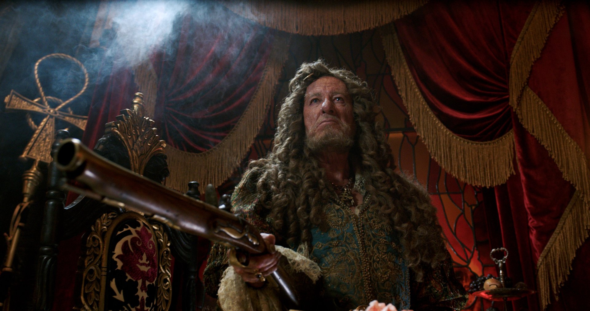 Hector Barbossa in ornate pirate costume from Pirates of the Caribbean: Dead Men Tell No Tales — dramatic HD PC desktop wallpaper with red curtains, gold trim and an antique musket.