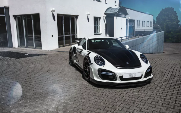 2K Quad HD PC wallpaper of a white Porsche 911 Turbo sports car parked by a modern building, front three-quarter view of the vehicle.