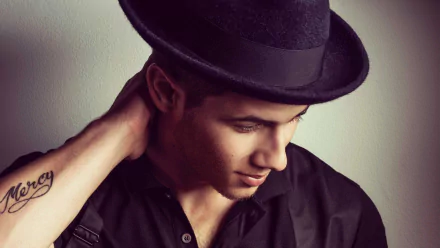 HD desktop wallpaper featuring a person in a black shirt and hat, glancing downward with a thoughtful expression.