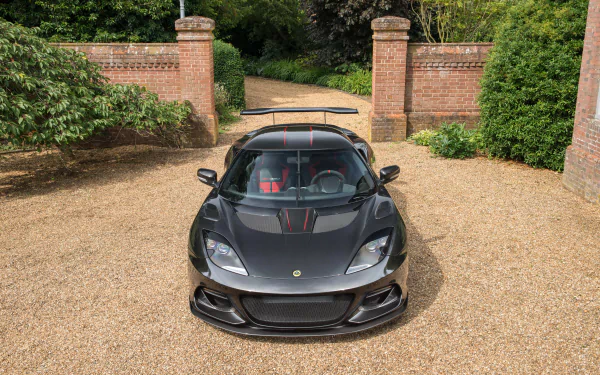 Front view of a silver Lotus Evora supercar parked on gravel before a brick gate — high-detail vehicle image rendered as a 4K Ultra HD PC desktop wallpaper/background.