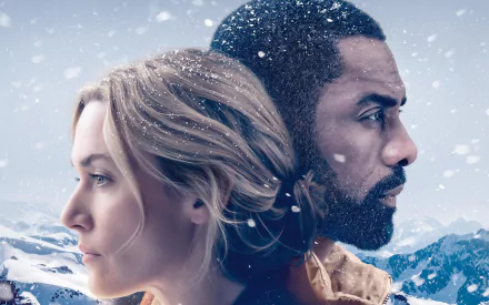 4K Ultra HD wallpaper featuring Kate Winslet and Idris Elba from the movie The Mountain Between Us, set against a snowy mountain backdrop.