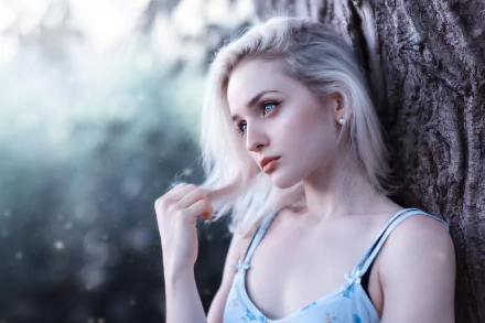 A blonde woman with blue eyes leans against a tree, captured with a depth of field effect, creating a moody atmosphere. The image is a high-definition desktop wallpaper/background.