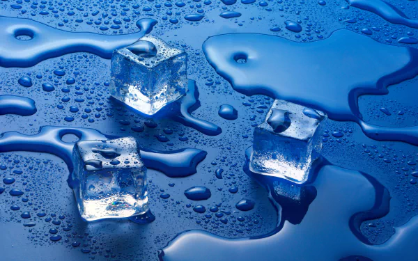 HD desktop wallpaper featuring three ice cubes on a blue surface with scattered water drops, showcasing vibrant blue tones and a refreshing, cool atmosphere.