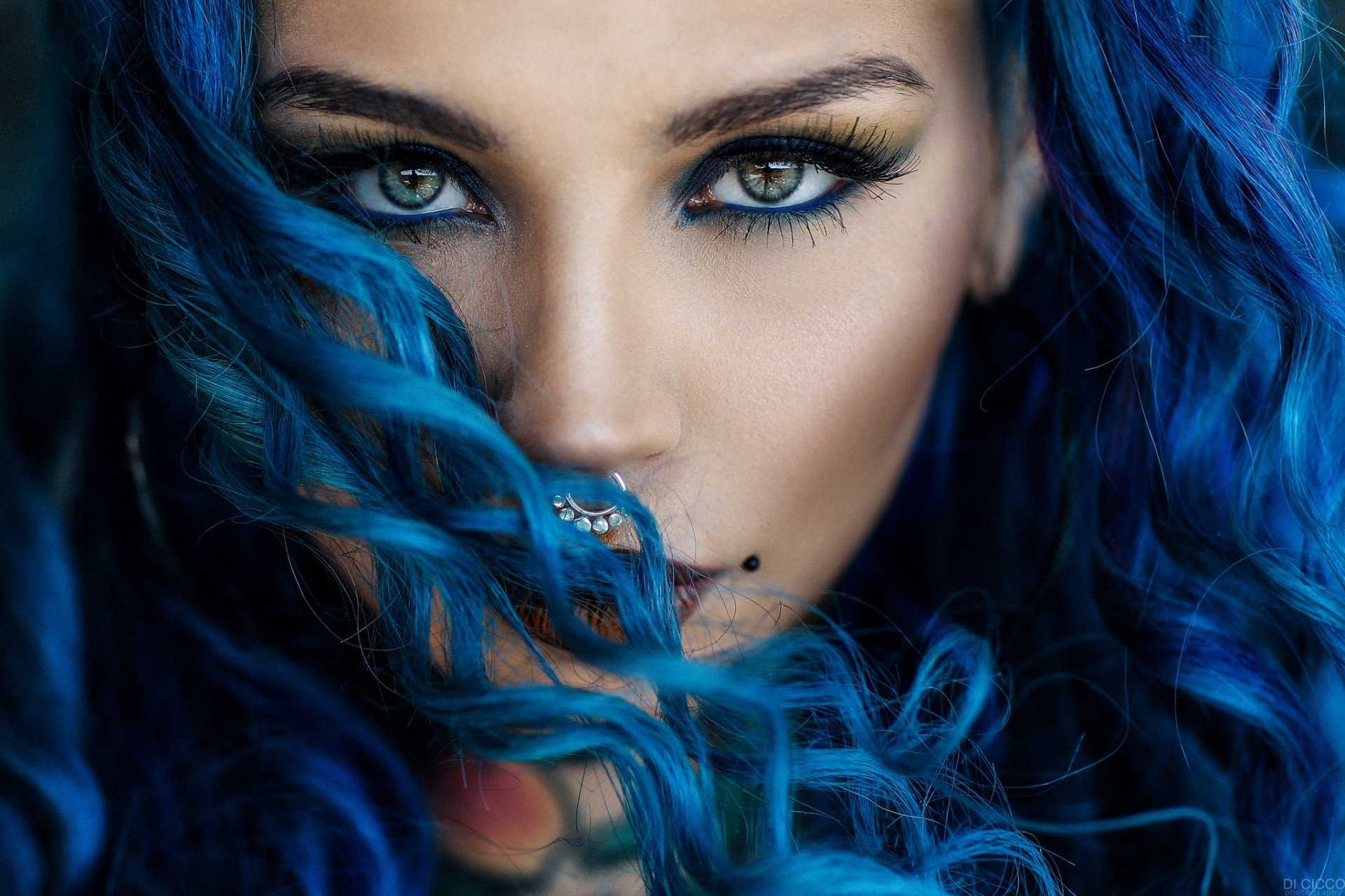 HD desktop wallpaper featuring a close-up of a woman with striking blue eyes and vibrant blue hair, accentuating her model-like appearance.