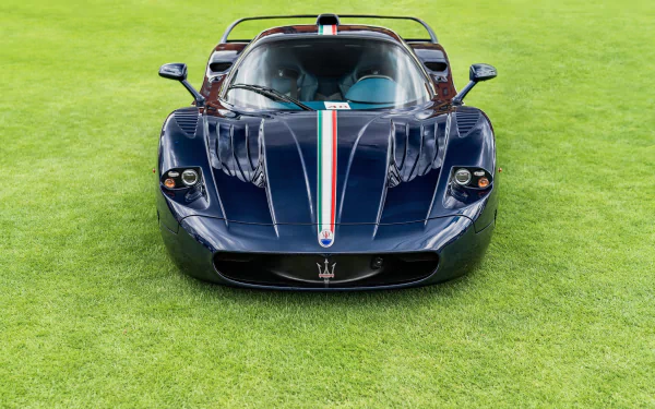 A blue Maserati MC12 supercar parked on vibrant green grass, showcased as a high-definition PC desktop wallpaper and background.
