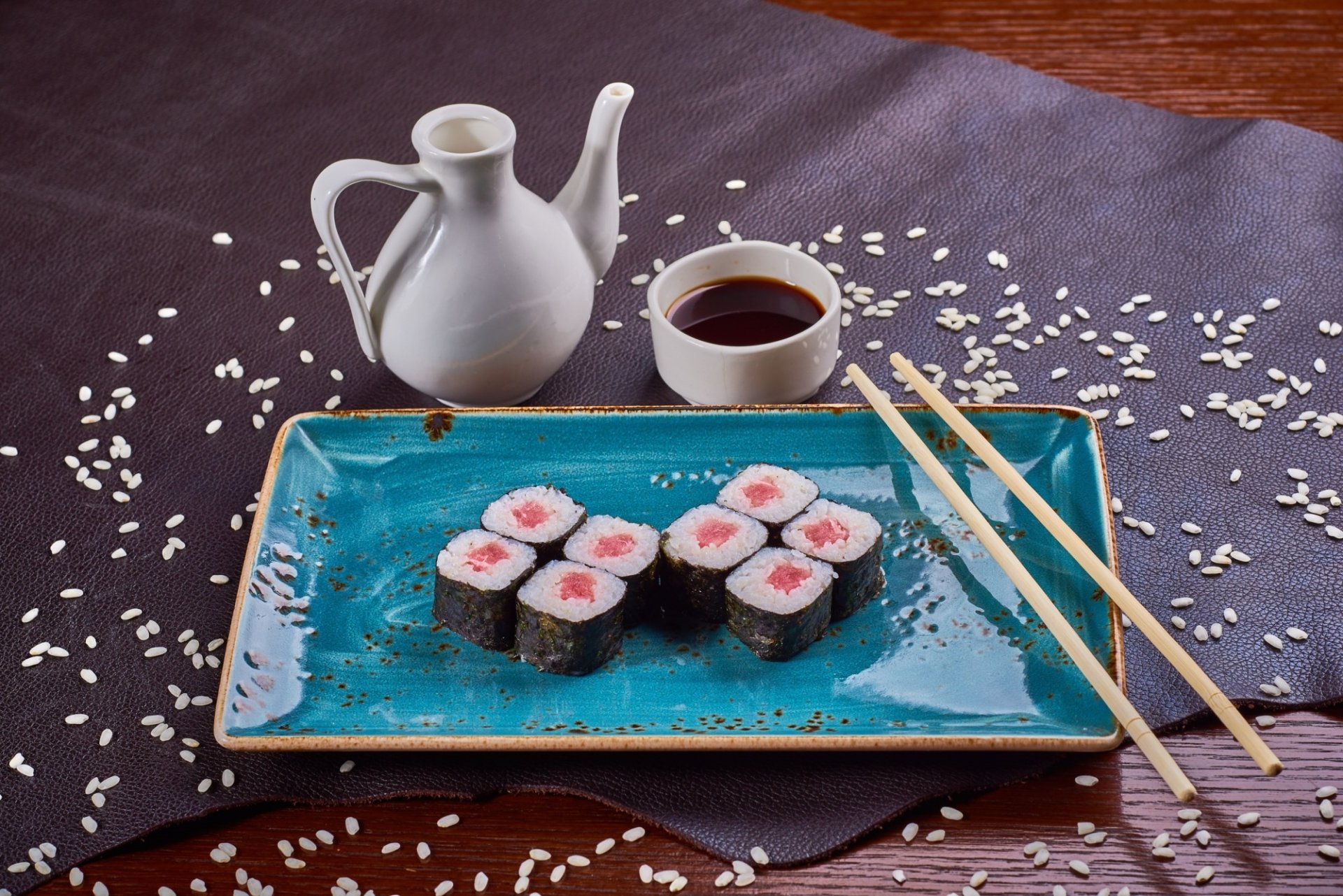 HD PC desktop wallpaper background still life: sushi rolls on a blue plate with chopsticks, scattered rice, soy and a sake pourer — seafood, fish, food.