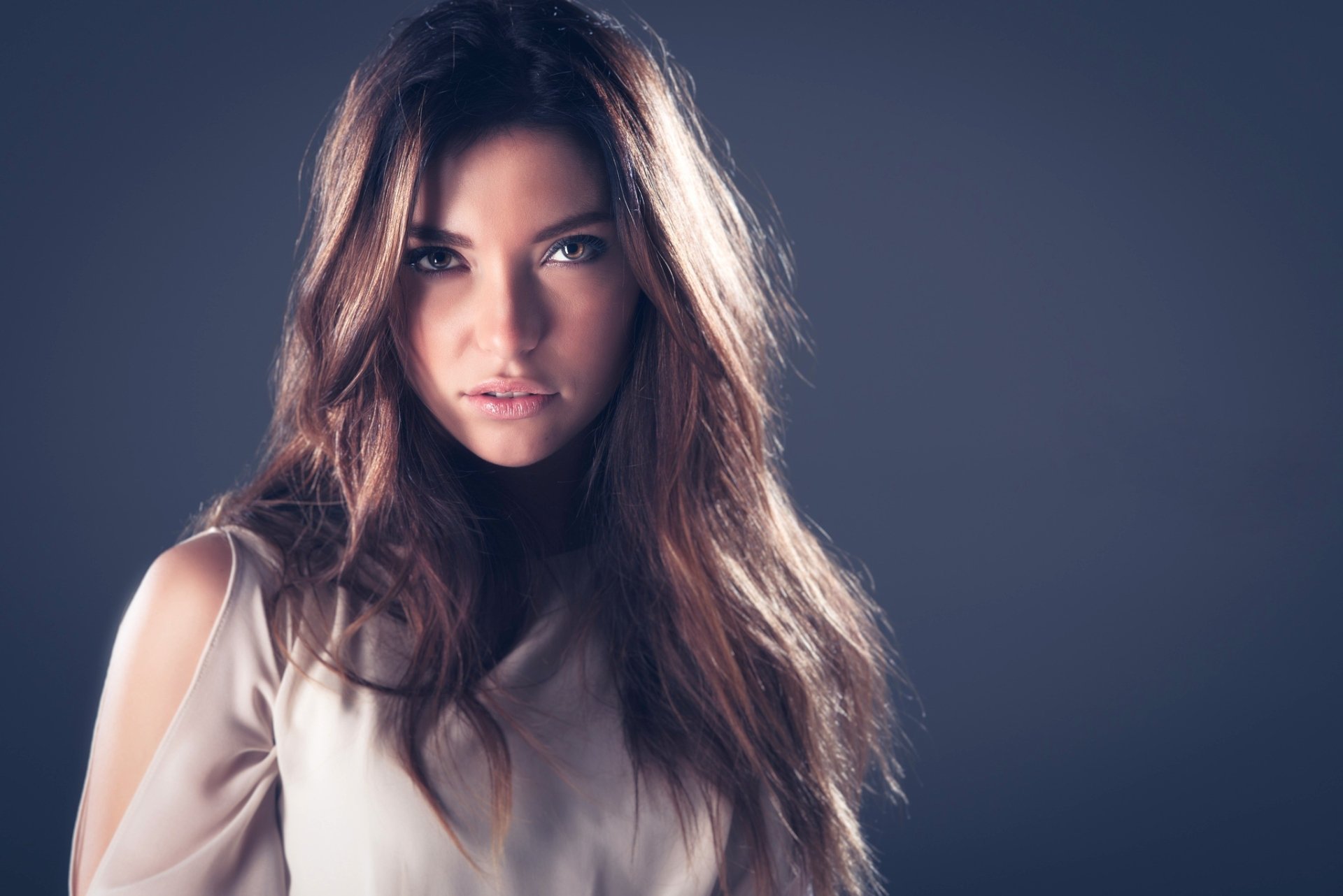 HD PC desktop wallpaper and background: close-up portrait of a brunette model woman with hazel eyes, soft lighting on her face and flowing hair against a muted gray backdrop.