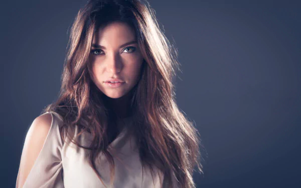HD PC desktop wallpaper and background: close-up portrait of a brunette model woman with hazel eyes, soft lighting on her face and flowing hair against a muted gray backdrop.