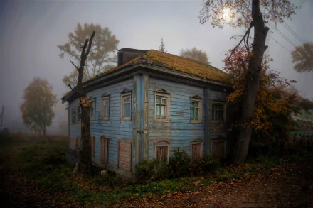 A haunting HD wallpaper of an abandoned house under the moonlight, shrouded in fog, and surrounded by bare trees at night.