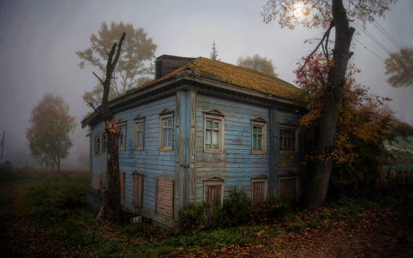 A haunting HD wallpaper of an abandoned house under the moonlight, shrouded in fog, and surrounded by bare trees at night.