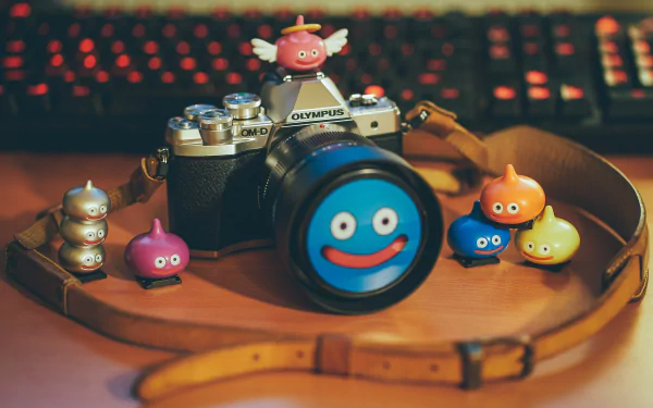 A 4K Ultra HD image of a man-made Olympus camera with a close-up lens, surrounded by colorful Dragon Quest Slime figurines on a wooden surface.