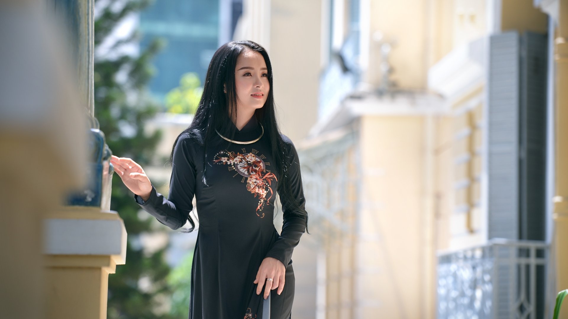 Brunette model in a black traditional dress, soft depth-of-field bokeh and sunlit outdoor background — 5K Ultra HD PC desktop wallpaper and background.