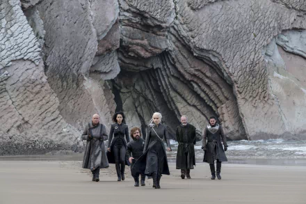 A high-definition desktop wallpaper featuring characters from the TV show Game of Thrones, including Jon Snow, Daenerys Targaryen, Tyrion Lannister, Missandei, Davos Seaworth, and Lord Varys, walking on a beach.