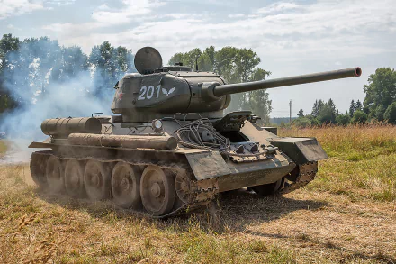 HD desktop wallpaper featuring a T-34 military tank moving across a grassy field with smoke and trees in the background.