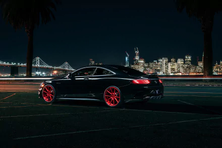 HD desktop wallpaper of a black Mercedes-Benz S-Class parked at night, with striking red wheels and a city skyline and illuminated bridge in the background.