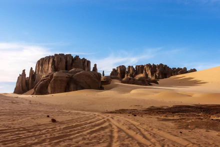 Tassili N'Ajjer in Tadrart, Algeria, showcases vast Sahara sand dunes and rocky formations within this African national park under a clear blue sky.
