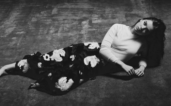 Black and white HD desktop wallpaper featuring American actress Hailee Steinfeld lying on the floor in a floral skirt and light top.