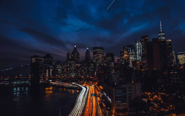 Nighttime time-lapse of New York City freeway with illuminated skyscrapers and bustling city lights, showcasing a vibrant urban skyline in the USA.