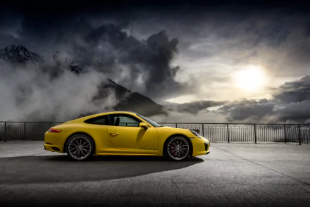 Yellow Porsche 911 Carrera 4S parked on a mountain overlook with dramatic cloudy sky, captured in stunning 4K Ultra HD for a PC desktop wallpaper.