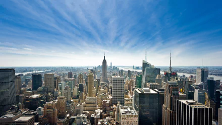 HD wallpaper of Manhattan's skyline, featuring a diverse array of skyscrapers under a clear, blue sky. The bustling cityscape of New York City, USA, is prominently displayed.