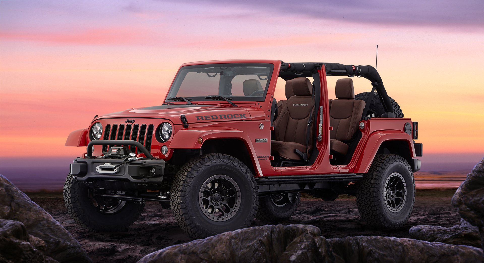 Red Jeep Wrangler off-road vehicle with doors removed, parked on rocky terrain against a colorful sunset — 2K Quad HD PC desktop wallpaper/background.