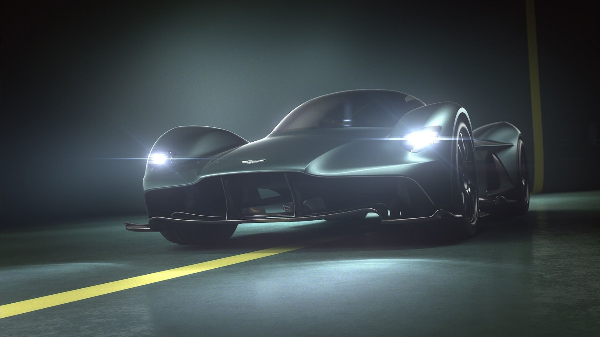 2K Quad HD PC desktop wallpaper of an Aston Martin Valkyrie vehicle: low-angle view of the supercar with headlights cutting through mist on a wet road.