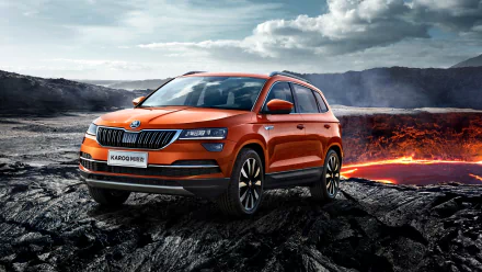 Orange Skoda Karoq SUV on rugged volcanic rock with glowing lava and dramatic clouds — 2K Quad HD PC desktop wallpaper background.