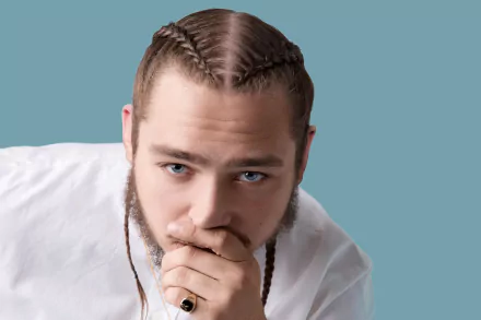 HD desktop wallpaper featuring a person with braided hair, tattoos, and a thoughtful expression against a blue background.