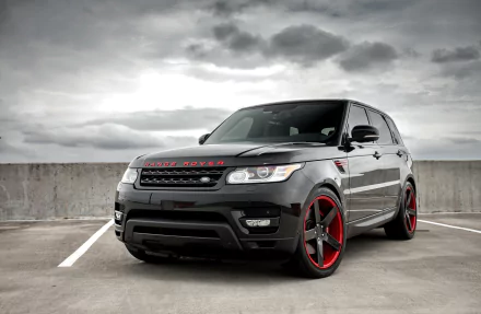 Black Range Rover SUV with red-accented rims parked in an empty lot under a cloudy sky, captured in 4K Ultra HD for a PC desktop wallpaper.