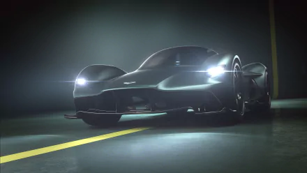 2K Quad HD PC desktop wallpaper of an Aston Martin Valkyrie vehicle: low-angle view of the supercar with headlights cutting through mist on a wet road.
