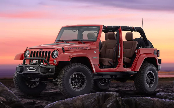 Red Jeep Wrangler off-road vehicle with doors removed, parked on rocky terrain against a colorful sunset — 2K Quad HD PC desktop wallpaper/background.