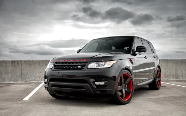 Black Range Rover SUV with red-accented rims parked in an empty lot under a cloudy sky, captured in 4K Ultra HD for a PC desktop wallpaper.