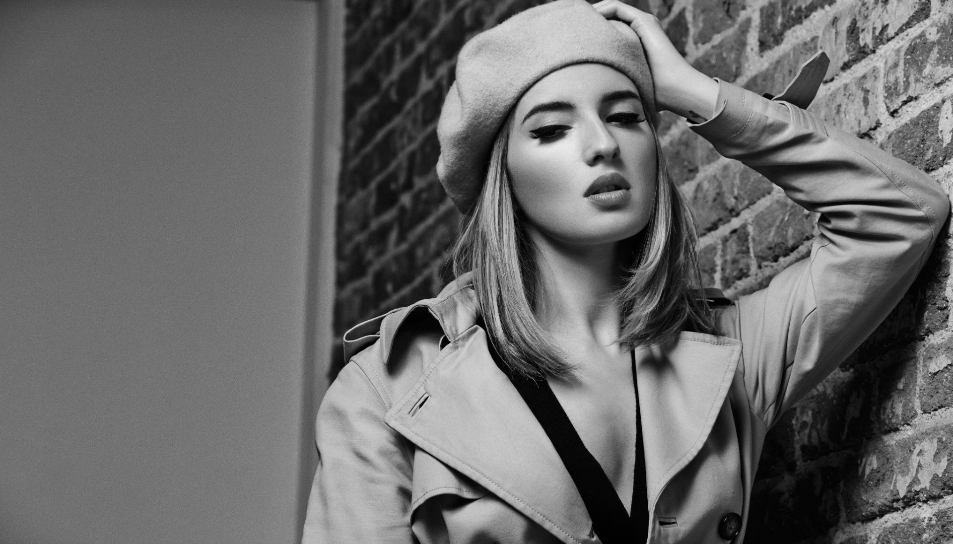 Black and white HD wallpaper featuring Spanish actress María Valverde wearing a beret and trench coat, posing against a brick wall.