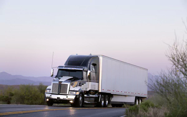 HD desktop wallpaper featuring a Western Star vehicle driving on a desert road at dawn with mountains and sparse vegetation in the background.