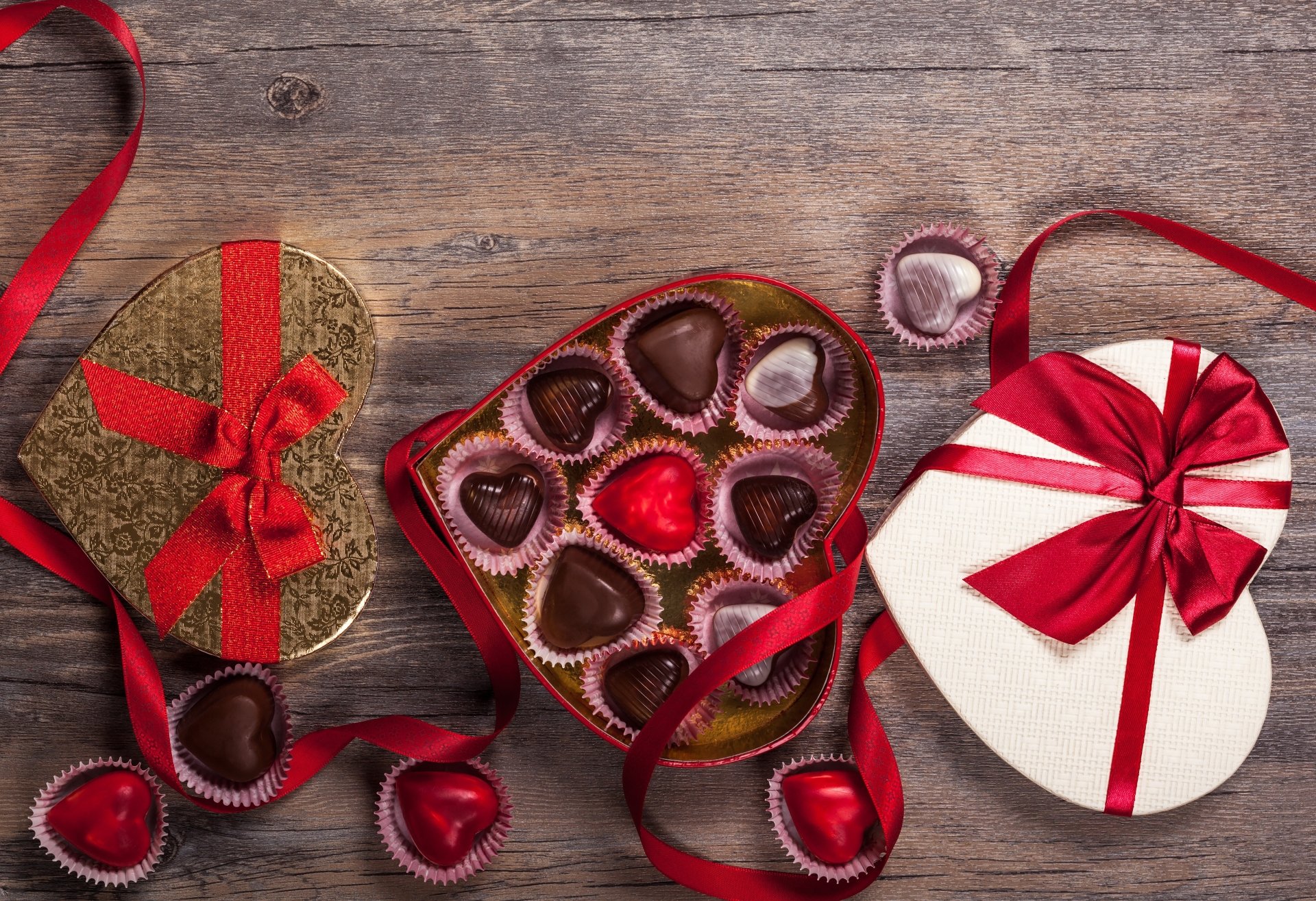 4K Ultra HD wallpaper featuring heart-shaped chocolates in decorative boxes with red ribbons, evoking a romantic Valentine's Day holiday theme.