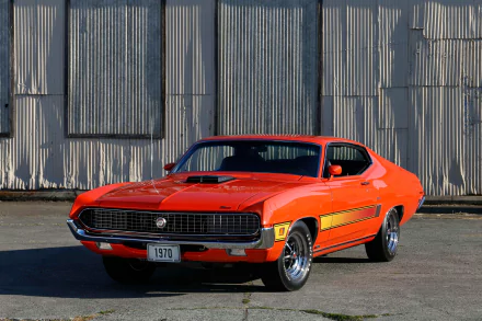 Bright orange 1970 Ford Torino vehicle parked in front of corrugated metal wall — high-resolution 4K Ultra HD PC desktop wallpaper and background.