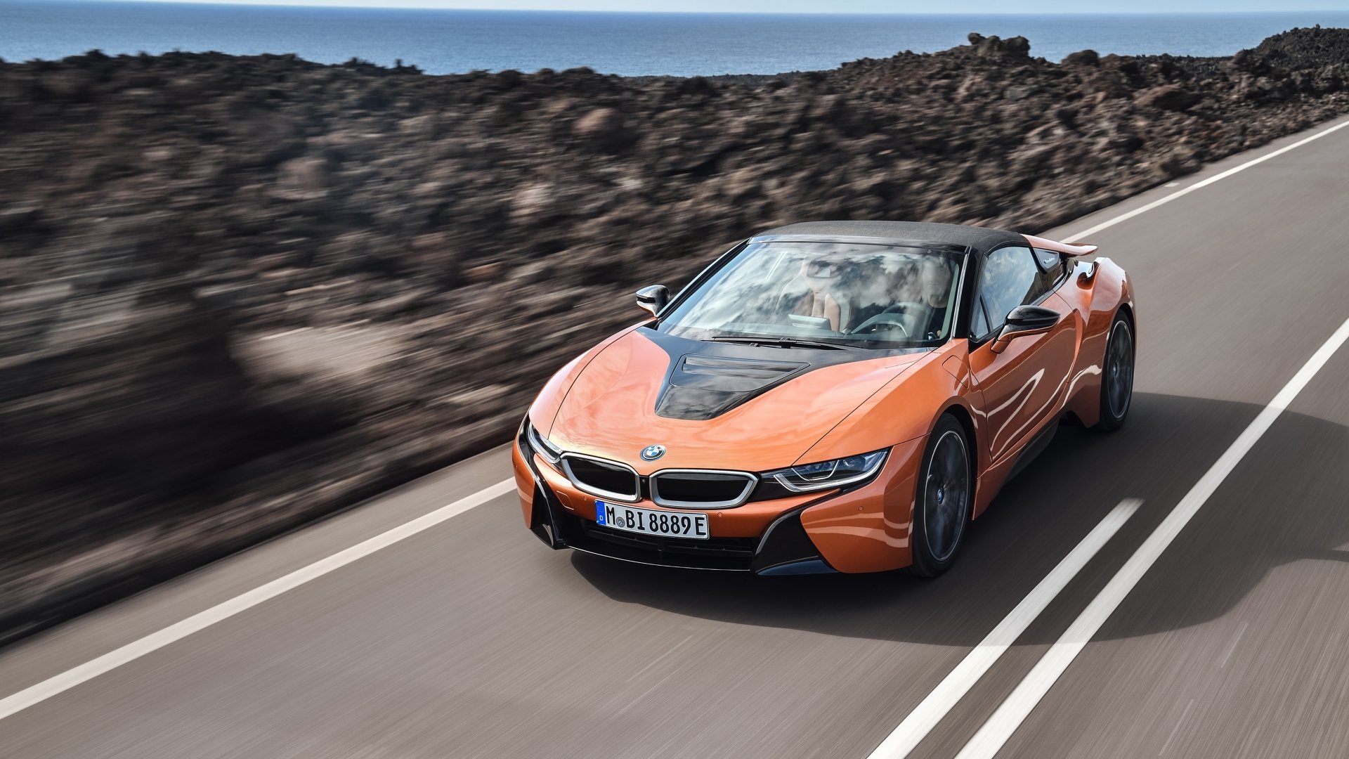 Orange BMW i8 supercar driving on a scenic road, featured as a 4K Ultra HD PC desktop wallpaper and background.